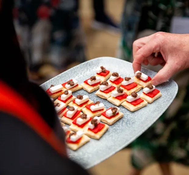 a hand taking a canapé dish from a serving plate